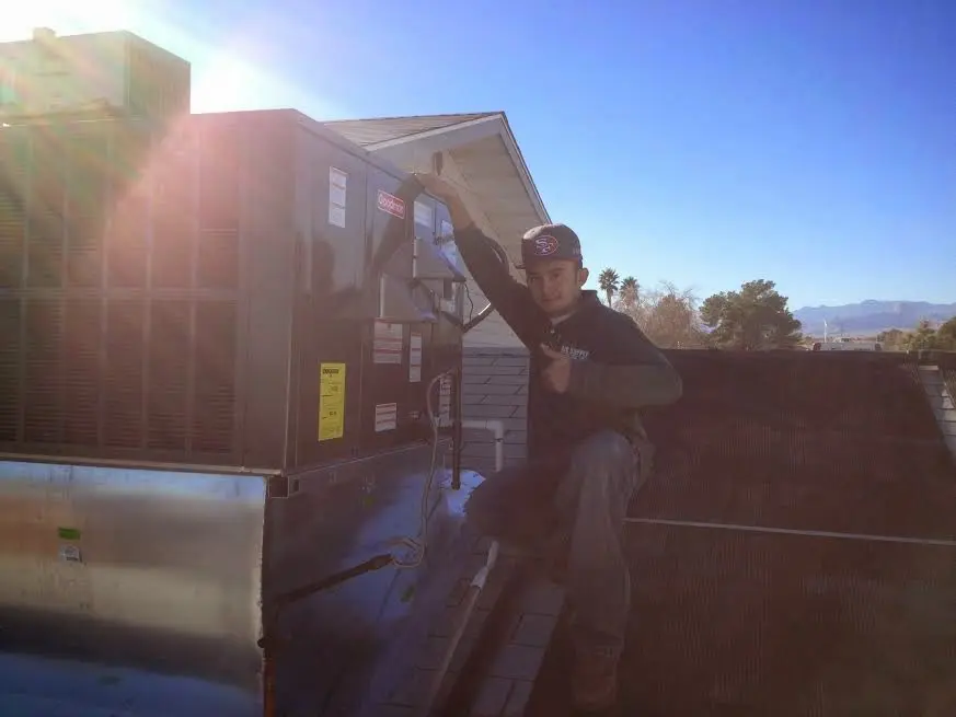 HVAC technician performing Air Duct Cleaning on a rooftop unit in Canton